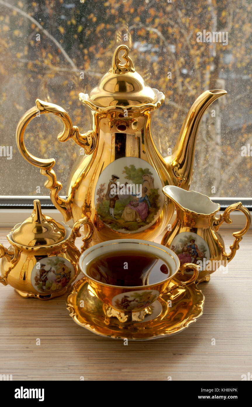 Beautiful gold-plated cup with tea stands on the windowsill Stock Photo