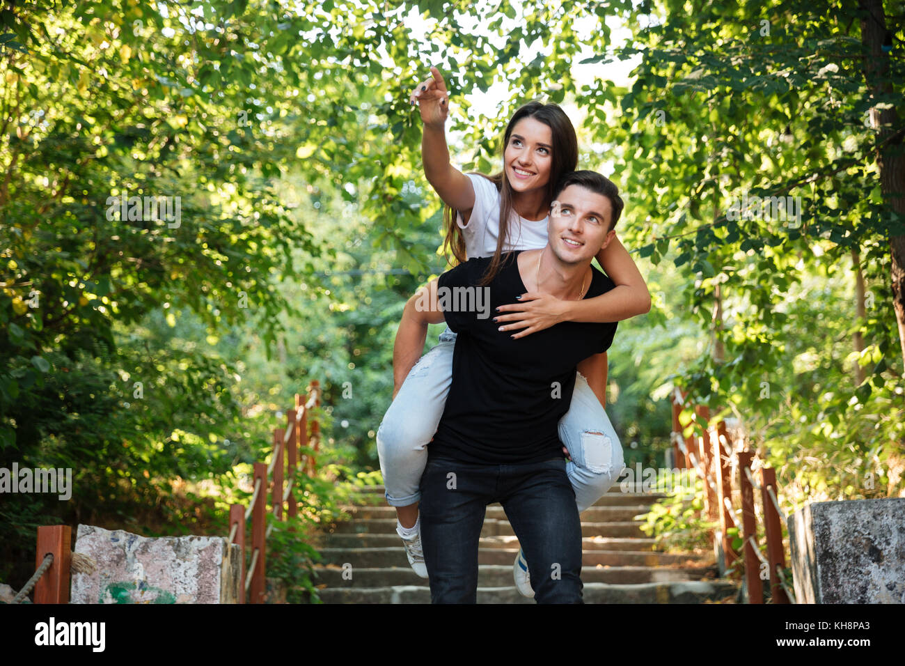 Young happy couple enjoying piggyback ride at the park outdoors ...