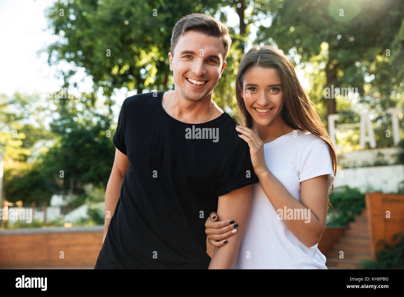 Portrait of a happy young couple in love hugging while standing at the ...