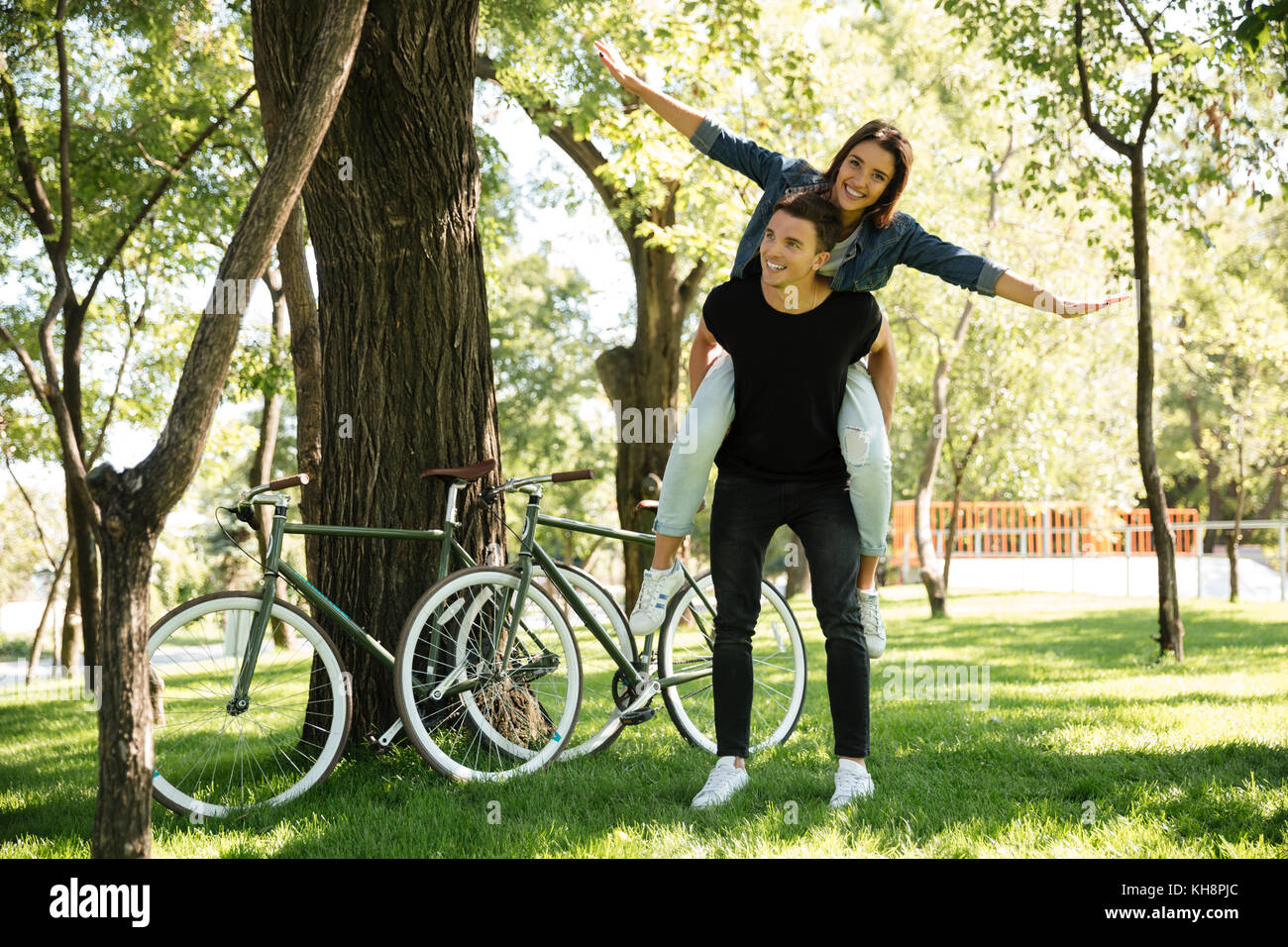Young cheerful couple enjoying piggyback ride at the park outdoors ...
