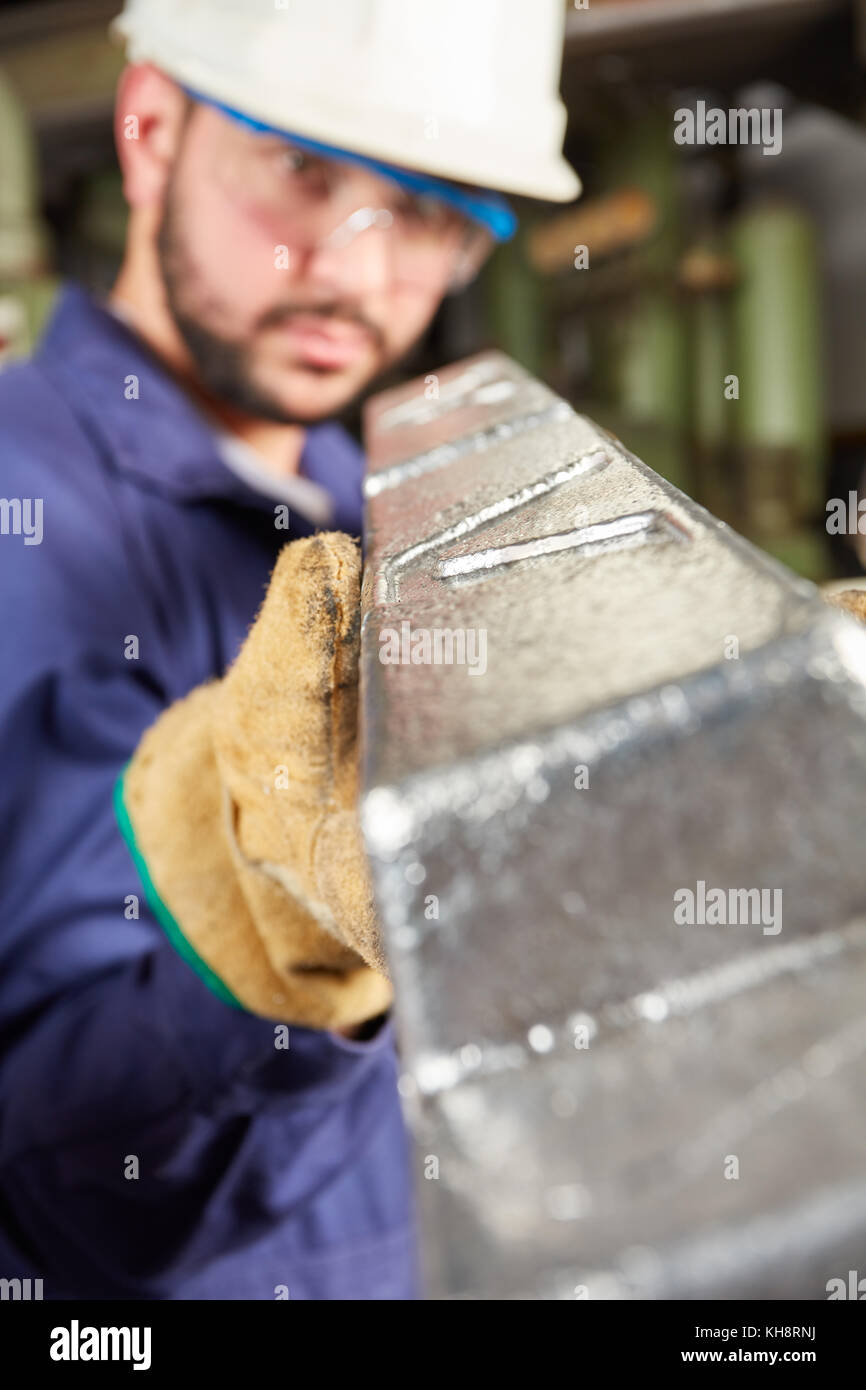 Foundry worker melt steel workpiece and controls quality Stock Photo