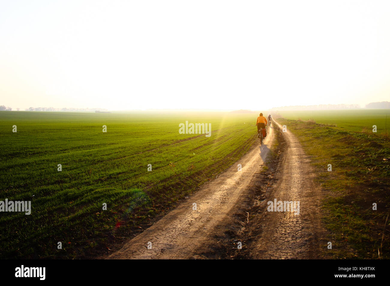 Female cyclist riding her bike on an open field during amazing sunset Stock Photo