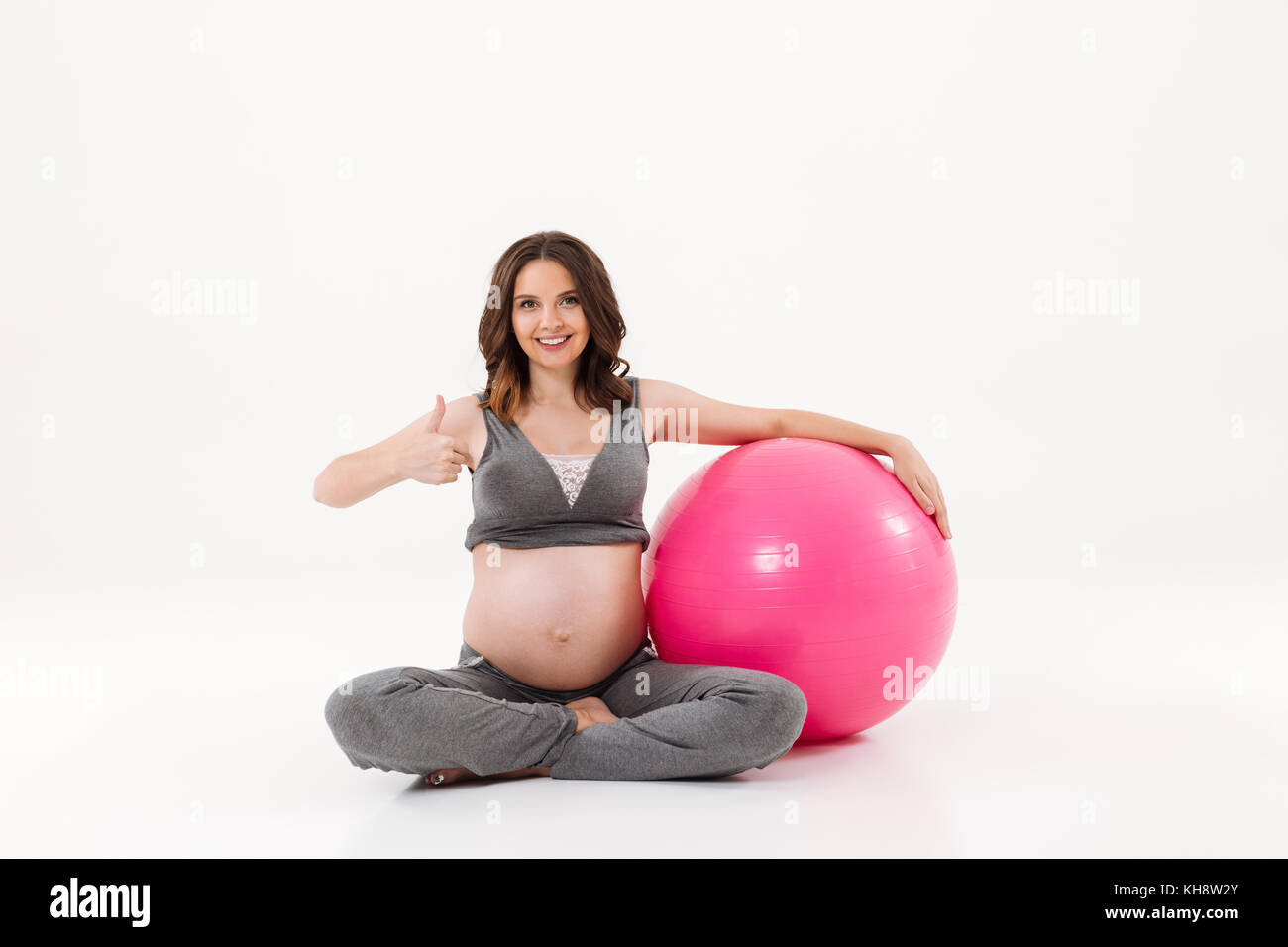 Smiling Pregnant Woman Sitting On The Floor With Fitball And