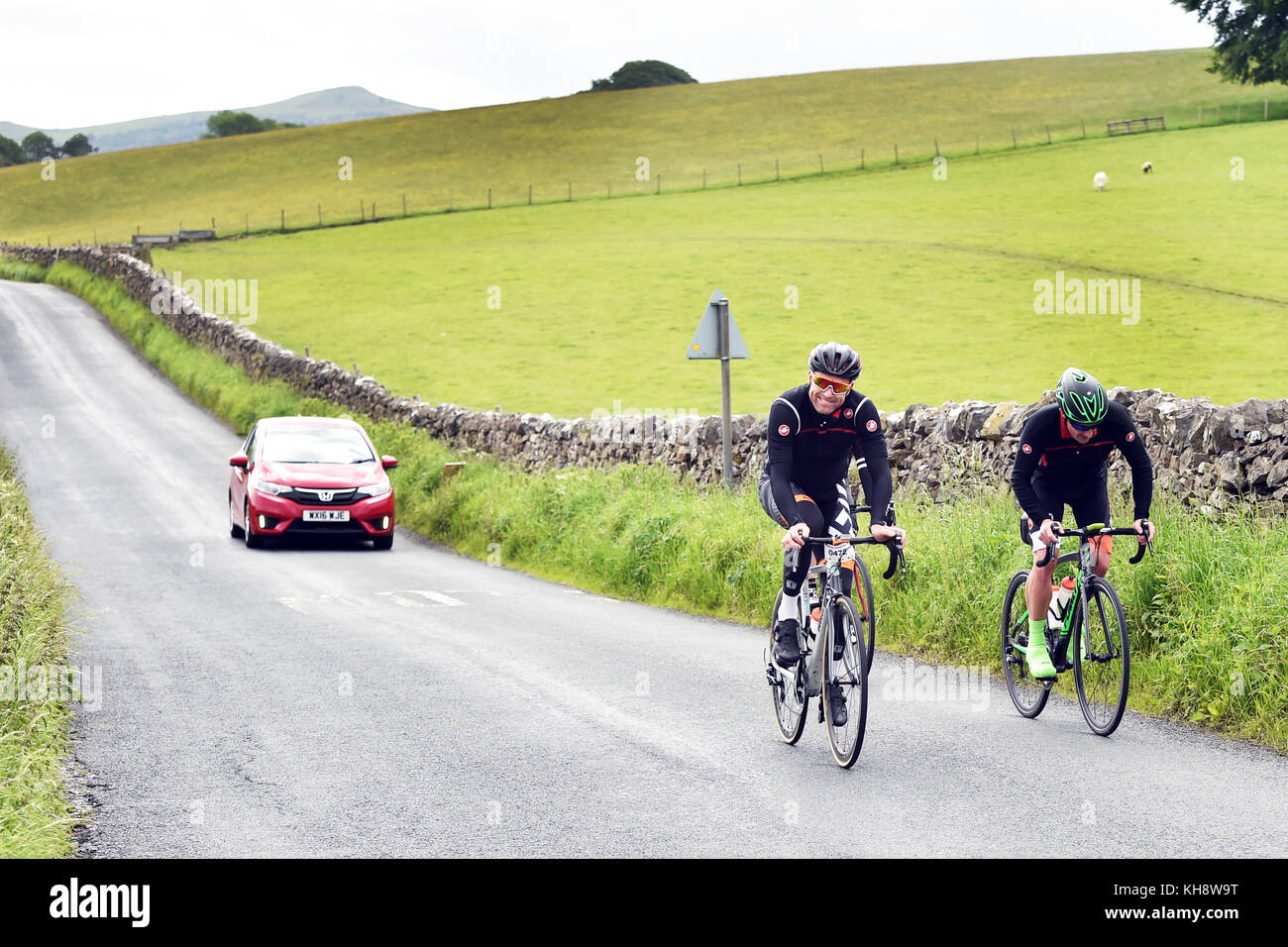 Cyclists cycling in a sportive along a country lane near Eshton, Yorkshire Dales UK Stock Photo
