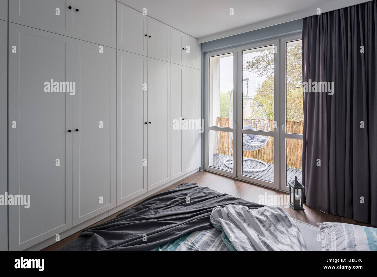 Modern Bedroom With Big White Wardrobe And Window Stock Photo
