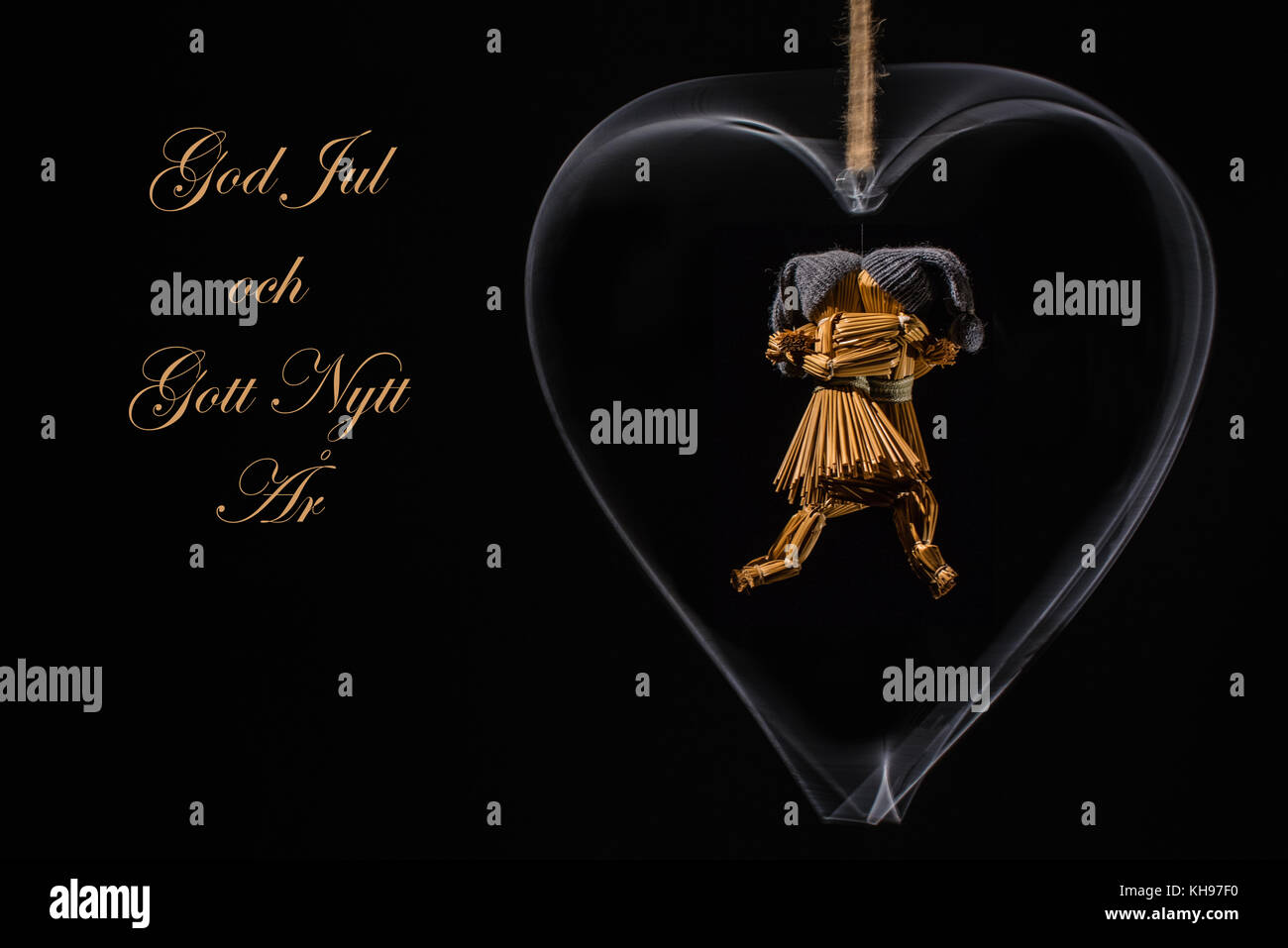 Christmas greetings in Swedish with dancing straw dolls in a rotating metal heart and with the text: God Jul och Gott Nytt År (=Merry Christmas and Ha Stock Photo