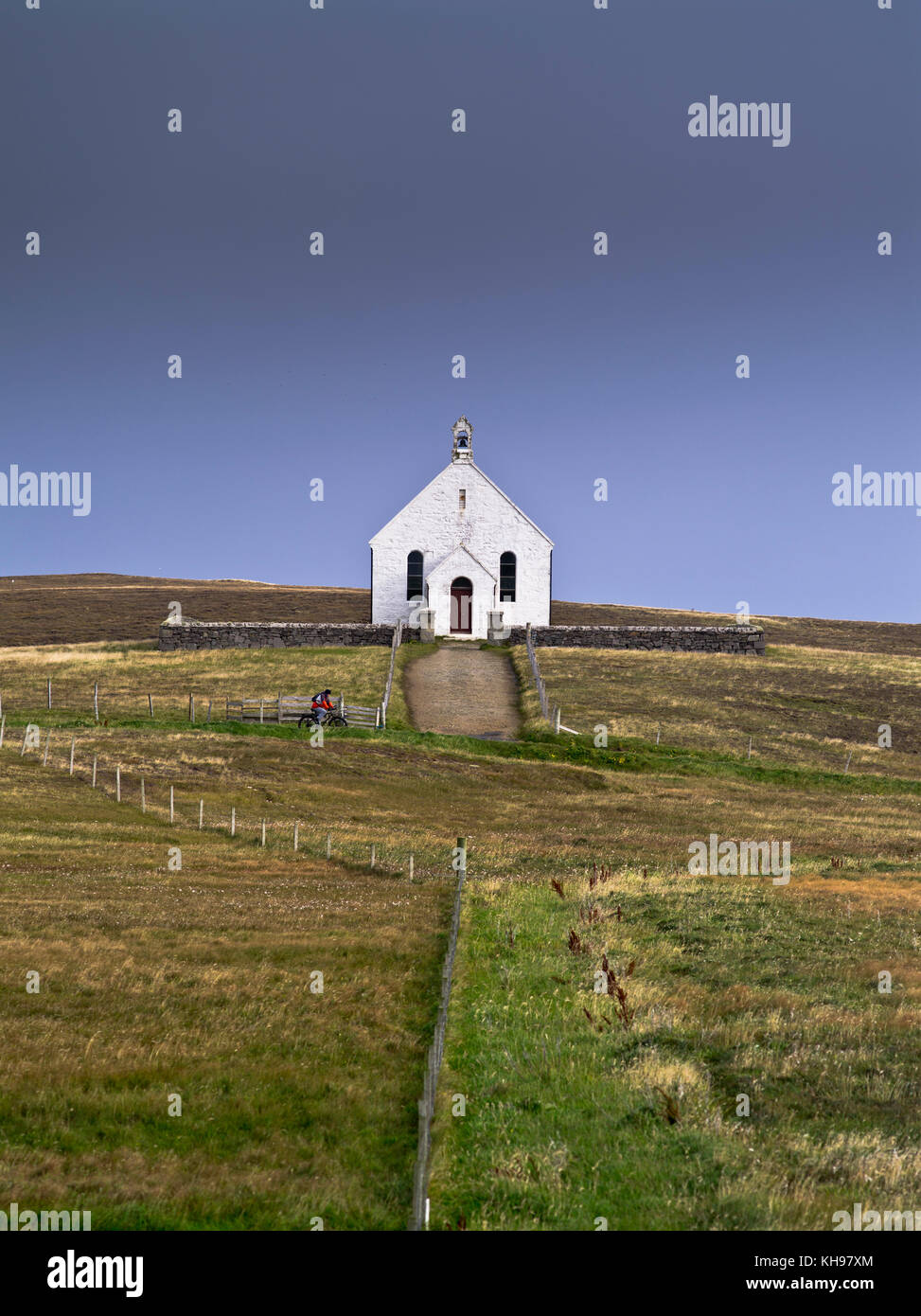 dh  KIRK FAIR ISLE Church of Scotland remote building stormy skies cyclist riding bike bicycle Stock Photo