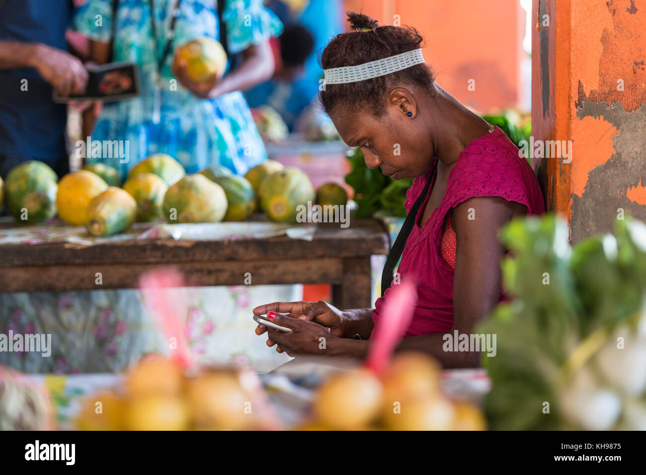 Woman stallholder using her mobile phone, Port Vila Fruit and Vegetable Market, late afternoon light. Vanuatu. Stock Photo