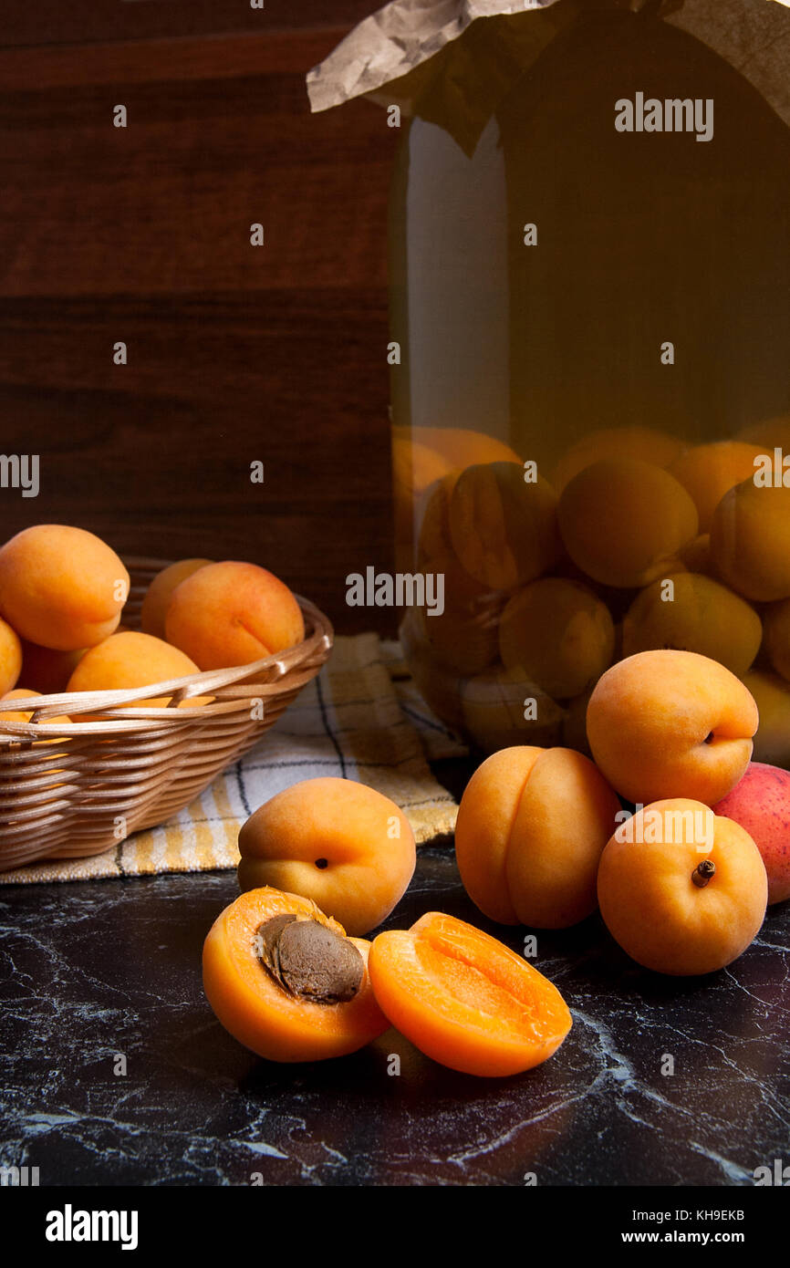 Ripe organic apricots harvested at summer time and big glass jar with
