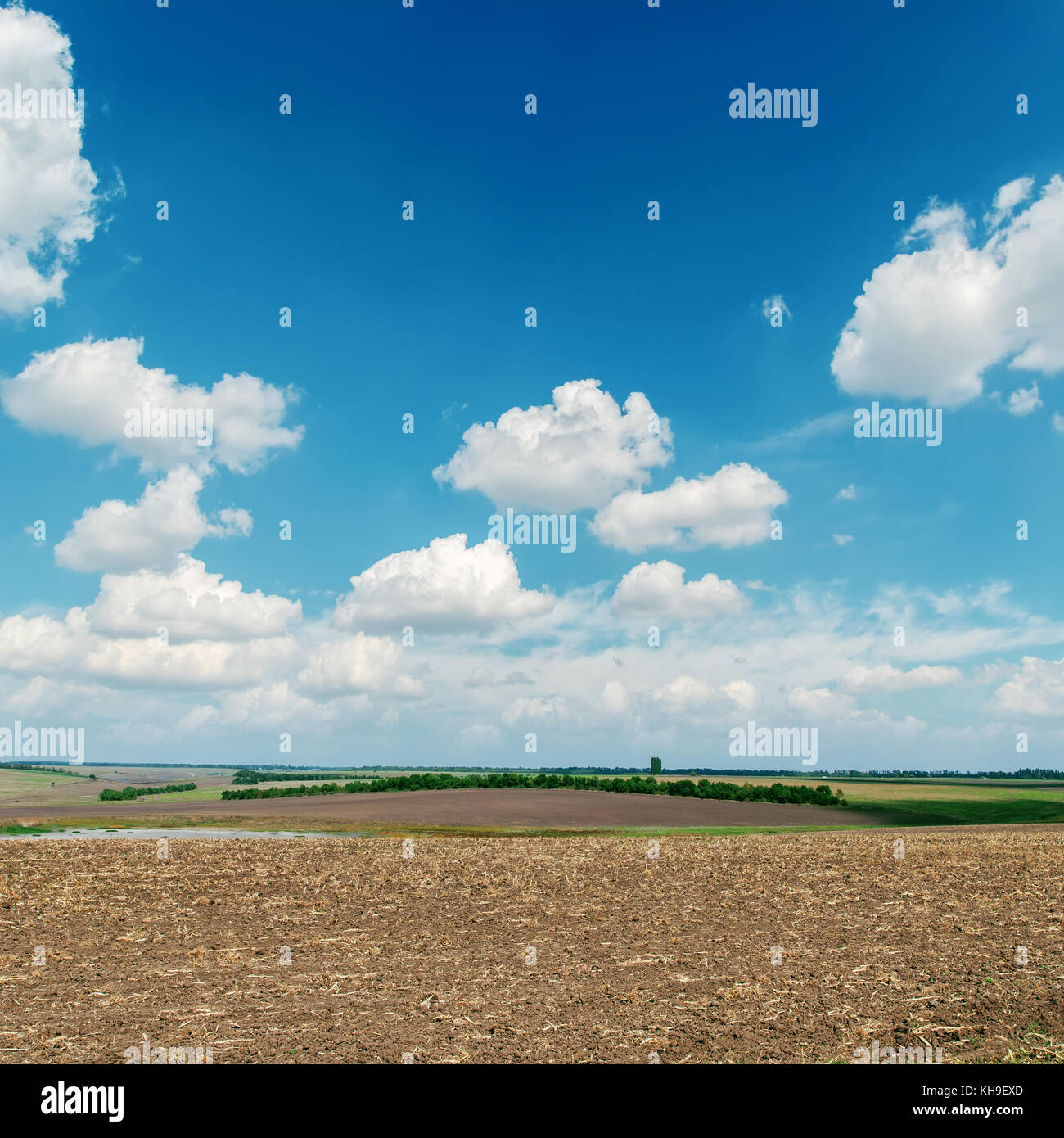 black plowed field under blue sky with white clouds Stock Photo - Alamy