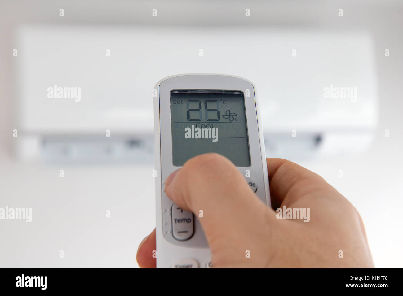 Hand with remote control directed on air conditioner. Air conditioner