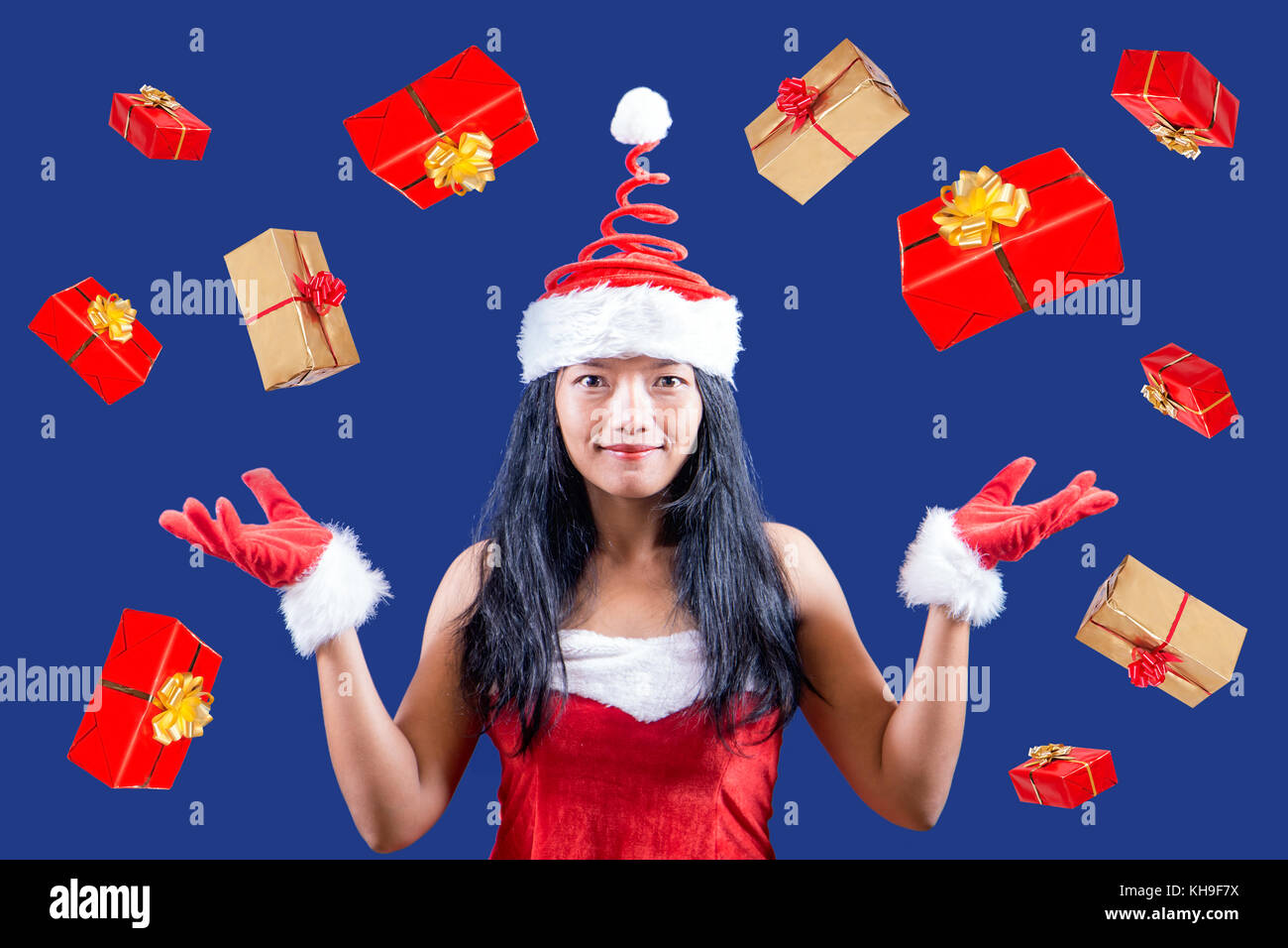 Cheerful Mrs. Claus looks at the camera and juggle with Christmas gifts. Xmas boxes are falling around Mrs. Santa Claus. Mrs Claus giving gifts. Stock Photo