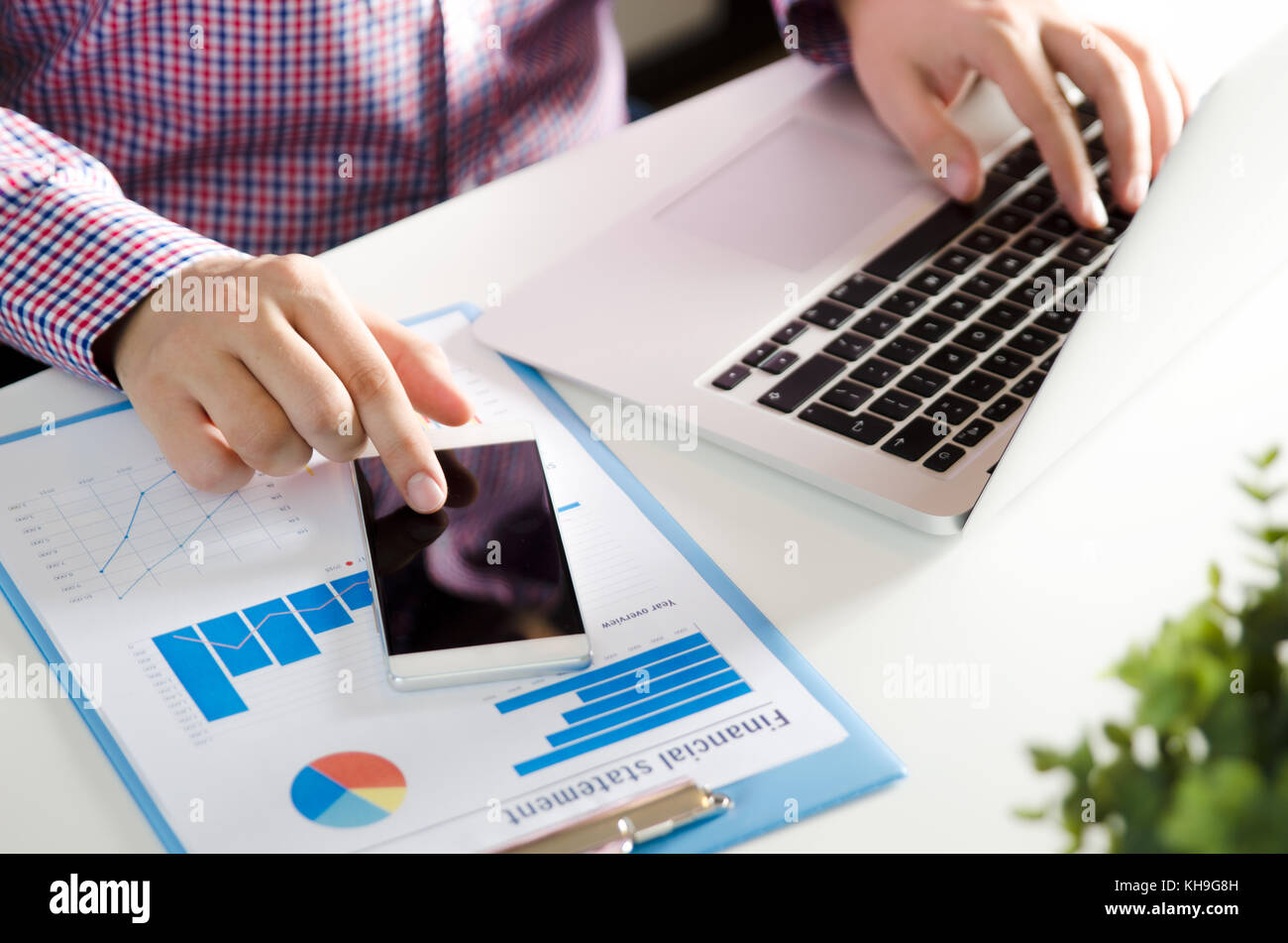 Man using mobile phone while working on laptop. Working with financial ...