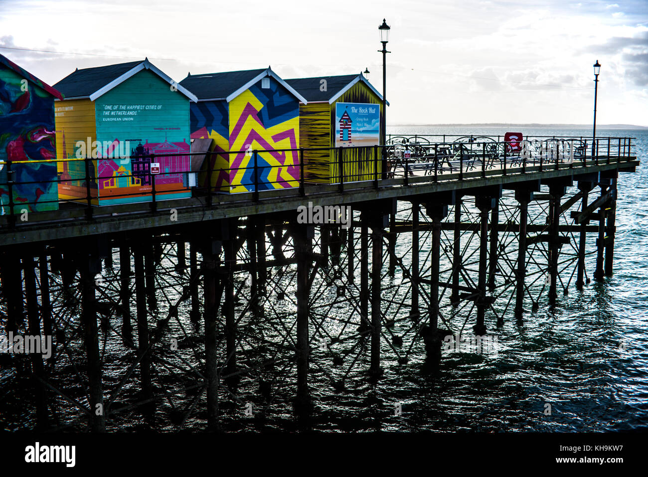 Brightly coloured huts on the end of Southend Pier with iron leg lattice structure looking towards the sun and Thames Estuary, Essex, UK Stock Photo