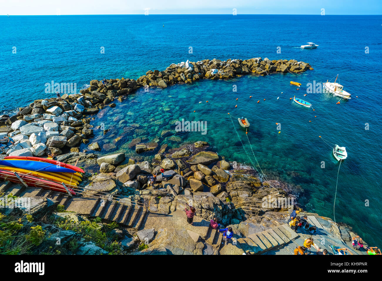 Small colorful rocky harbor near Monterosso Al Mare on the Ligurian coast of Italy in Cinque Terre with boats, kayaks and tourists Stock Photo