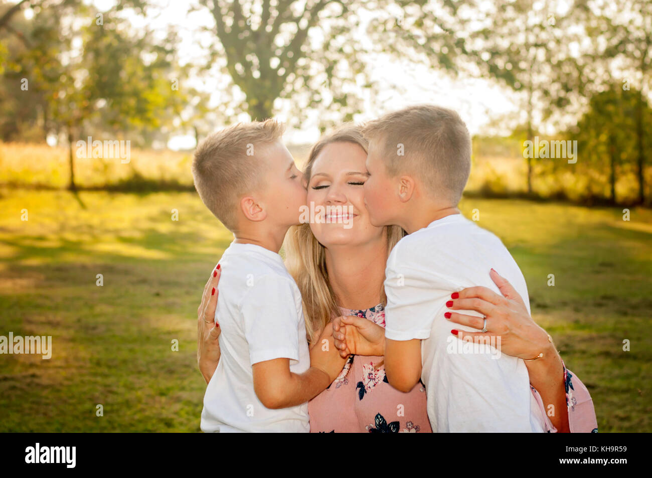 twin boys kissing mom Stock Photo