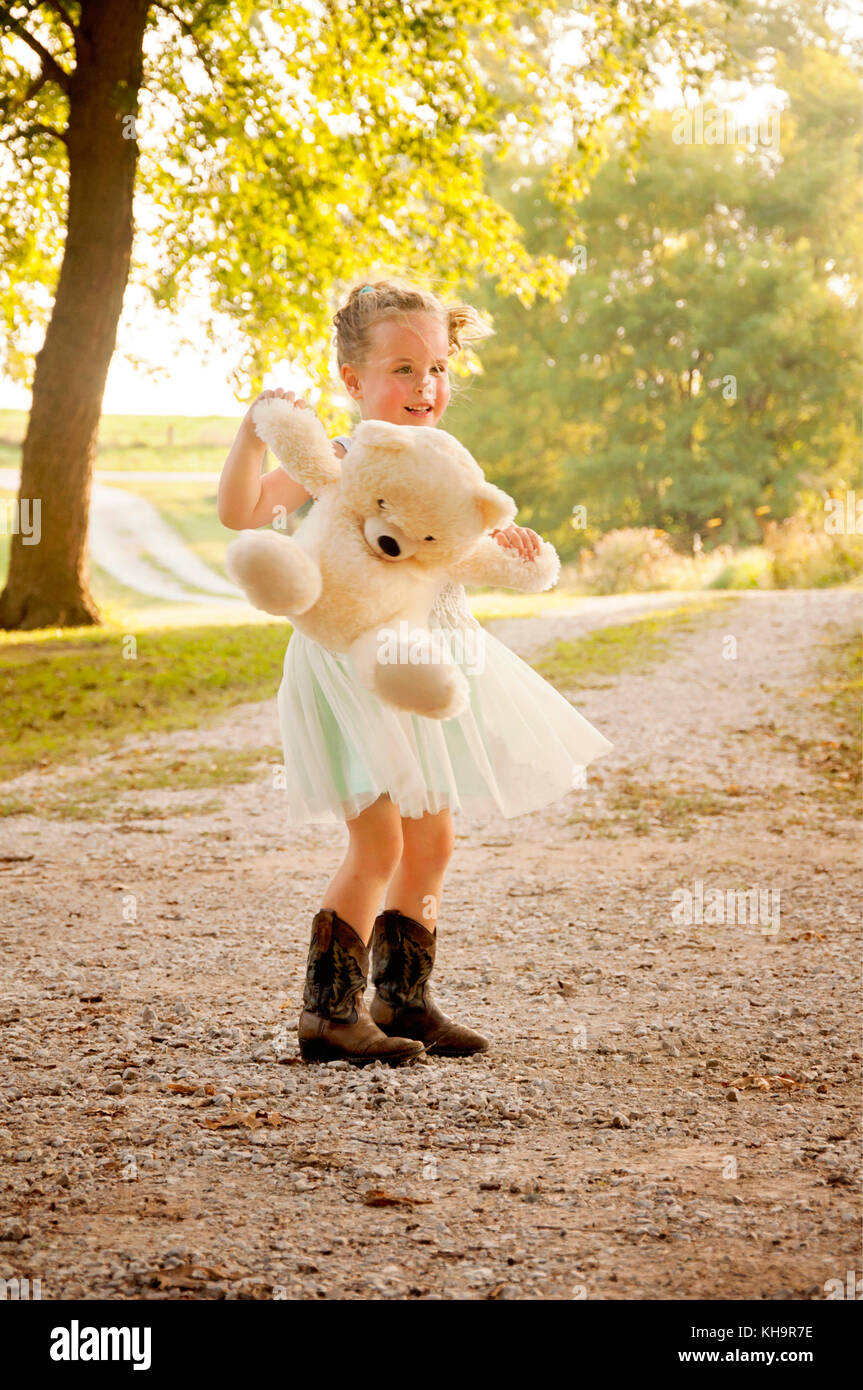 girl swinging stuffed bear and dancing rural setting Stock Photo