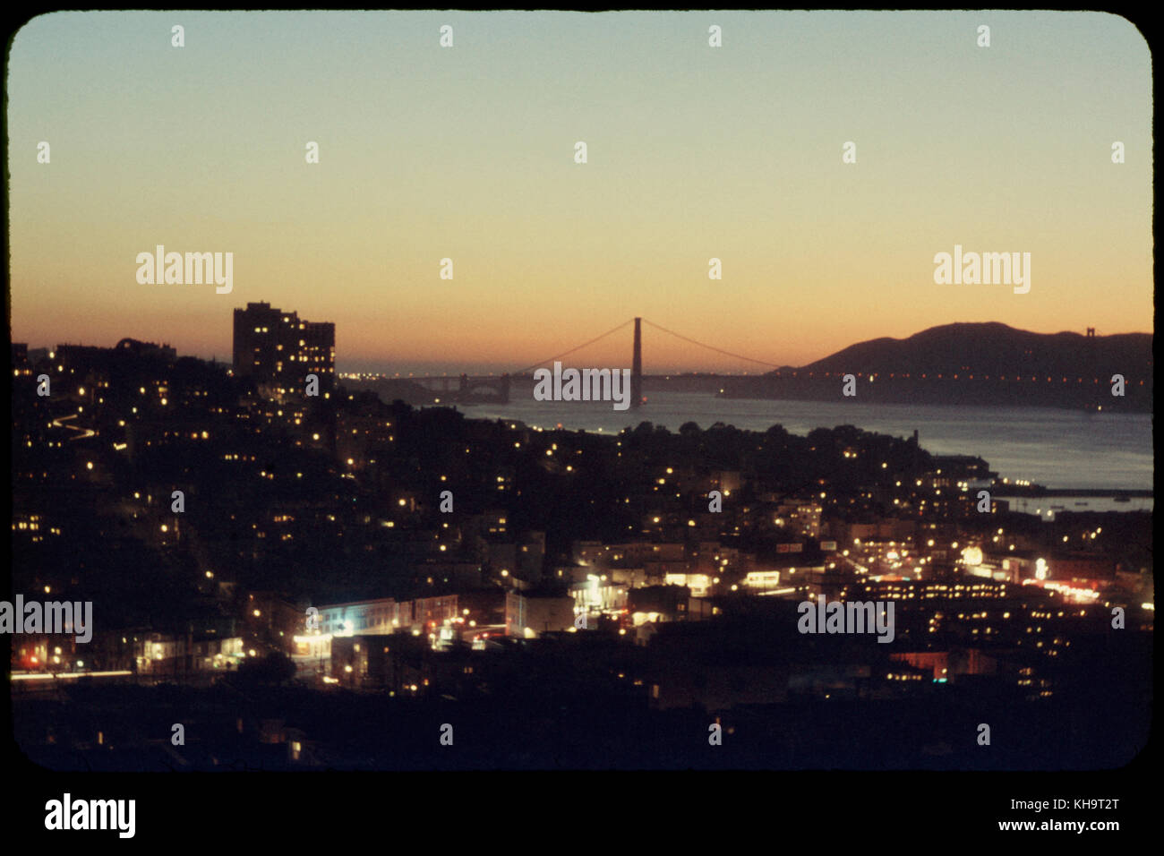 Illuminated Cityscape with Golden Gate Bridge in Background at Sunset, San Francisco, California, USA, 1957 Stock Photo
