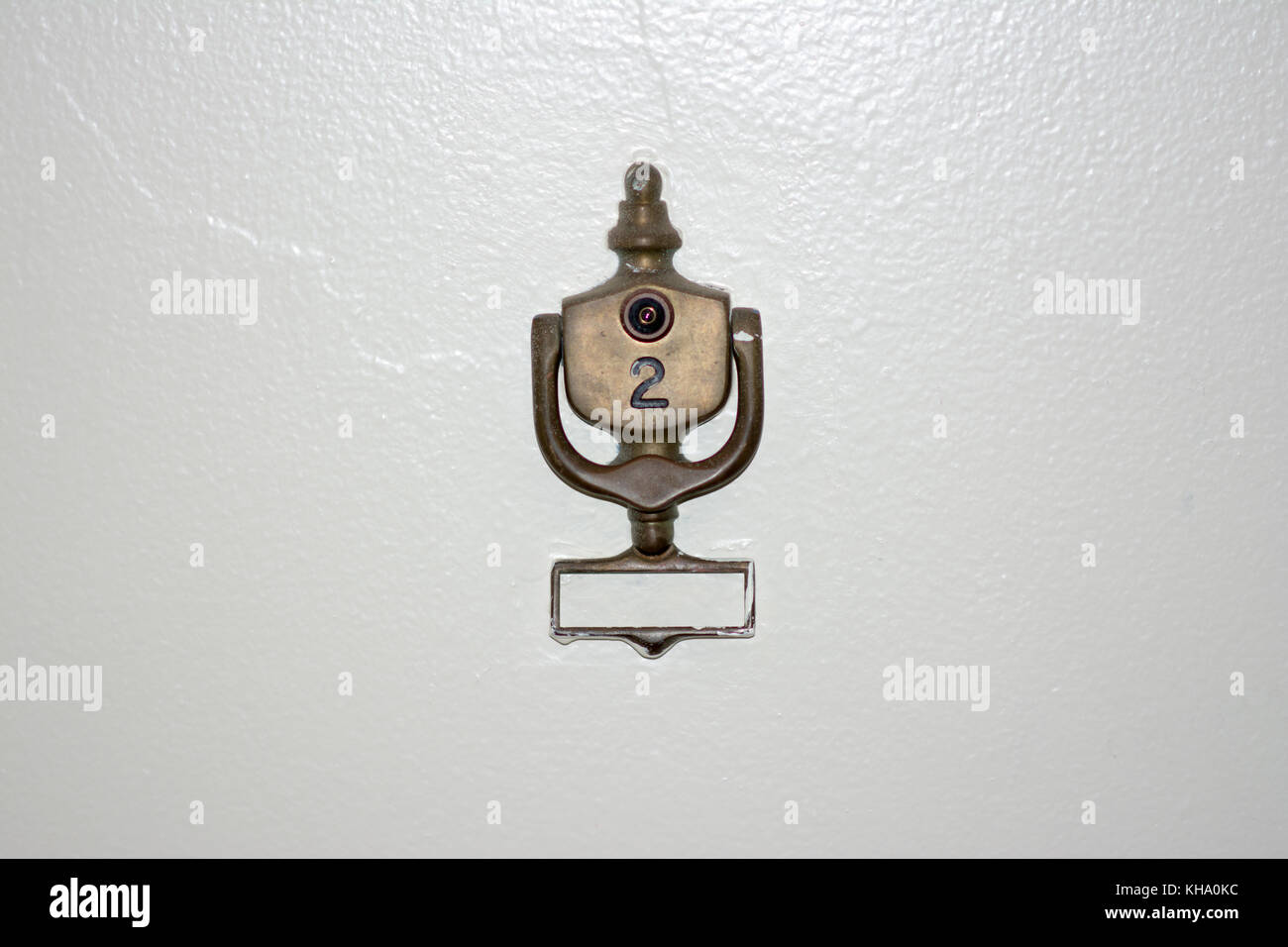 brass door knocker on door number 2 with peep hole on white door Stock