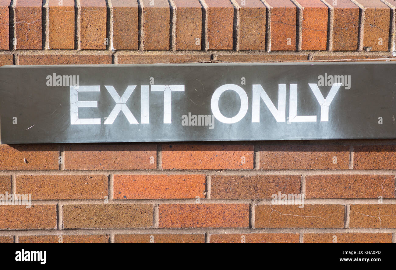 exit only sign affixed to a red brick wall. Stock Photo