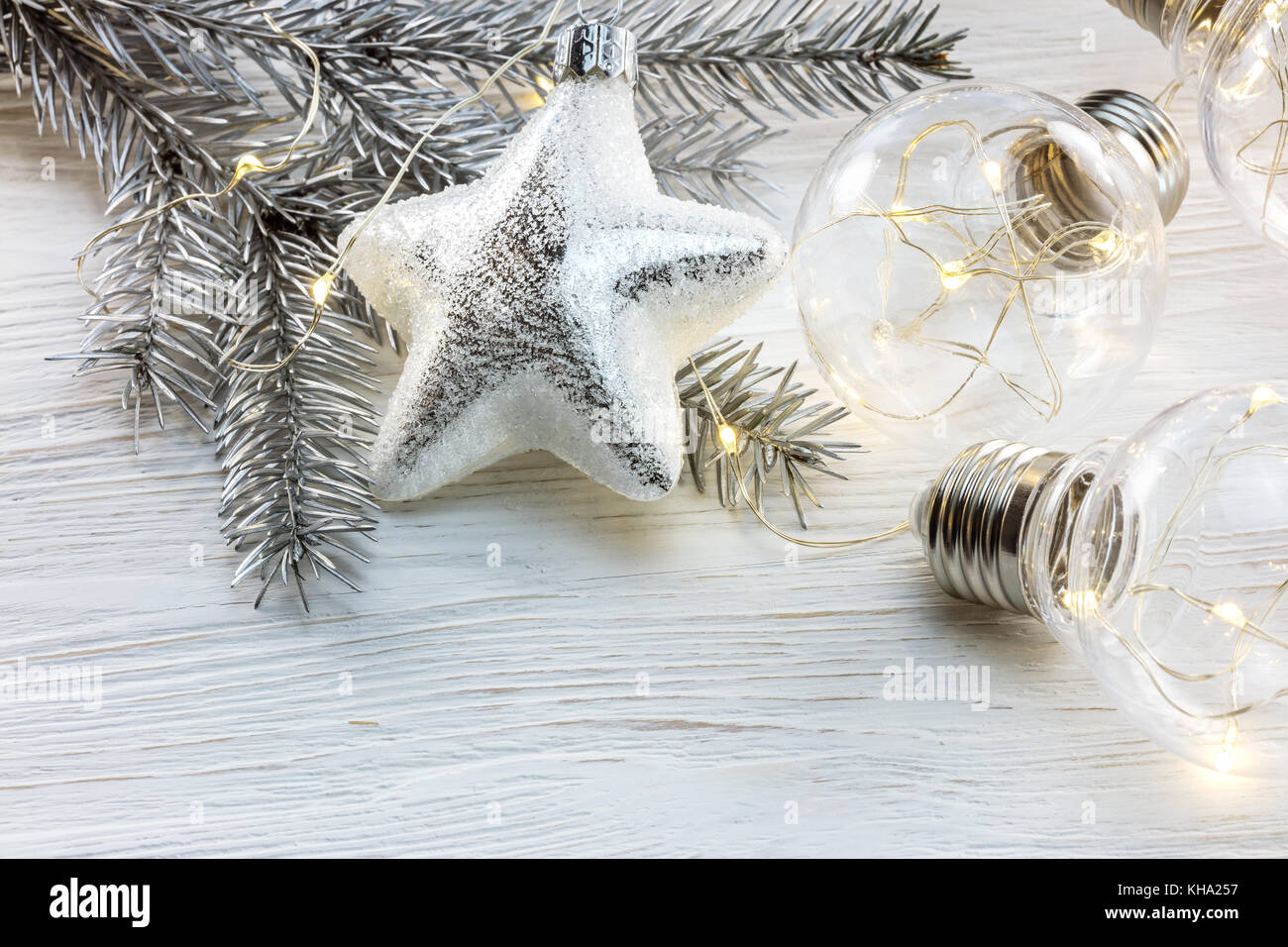 silver christmas tree branch, decorations and glowing light lamps on ...