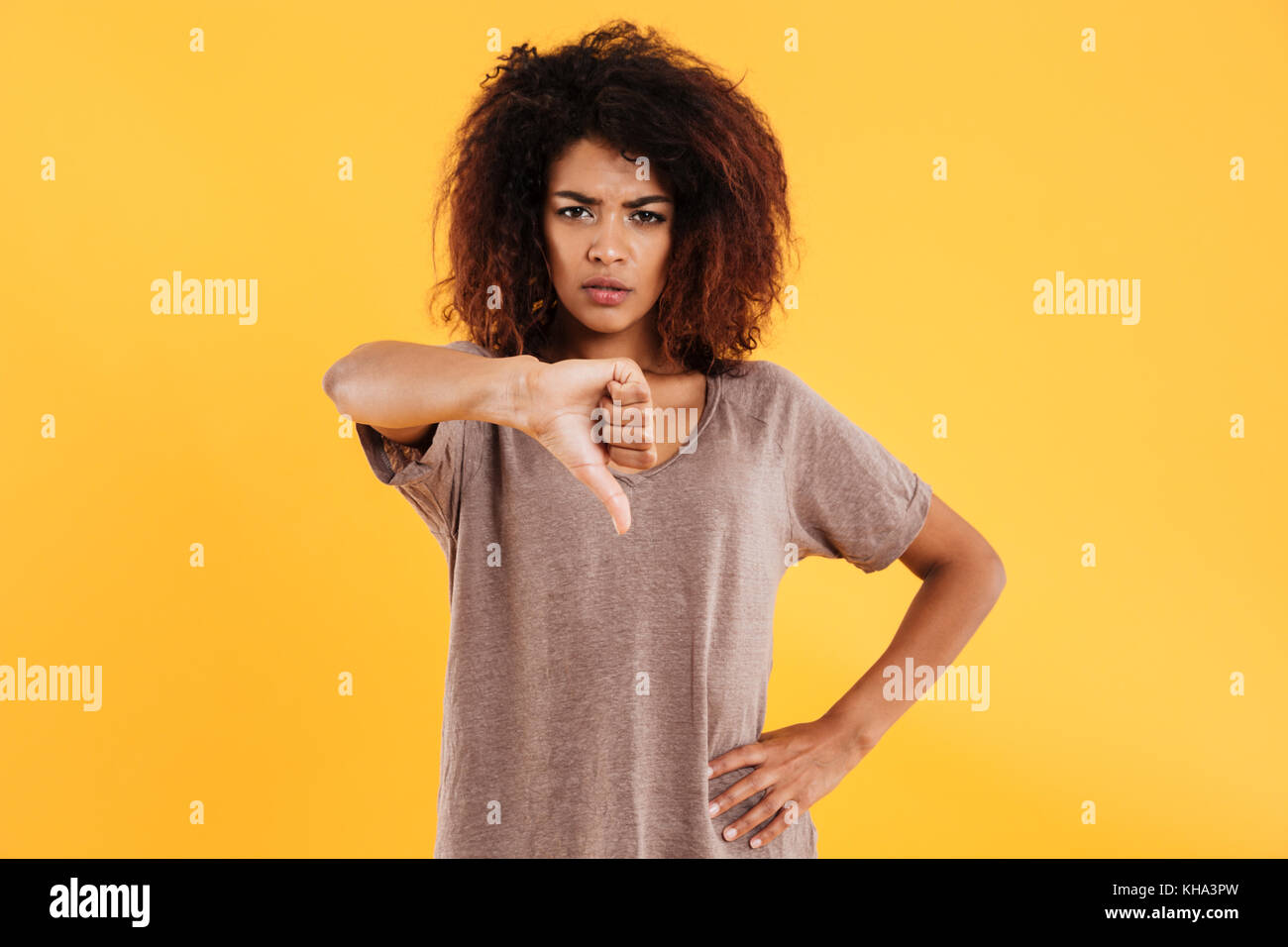 Young afro-american angry unhappy woman with curly hair showing thumb ...