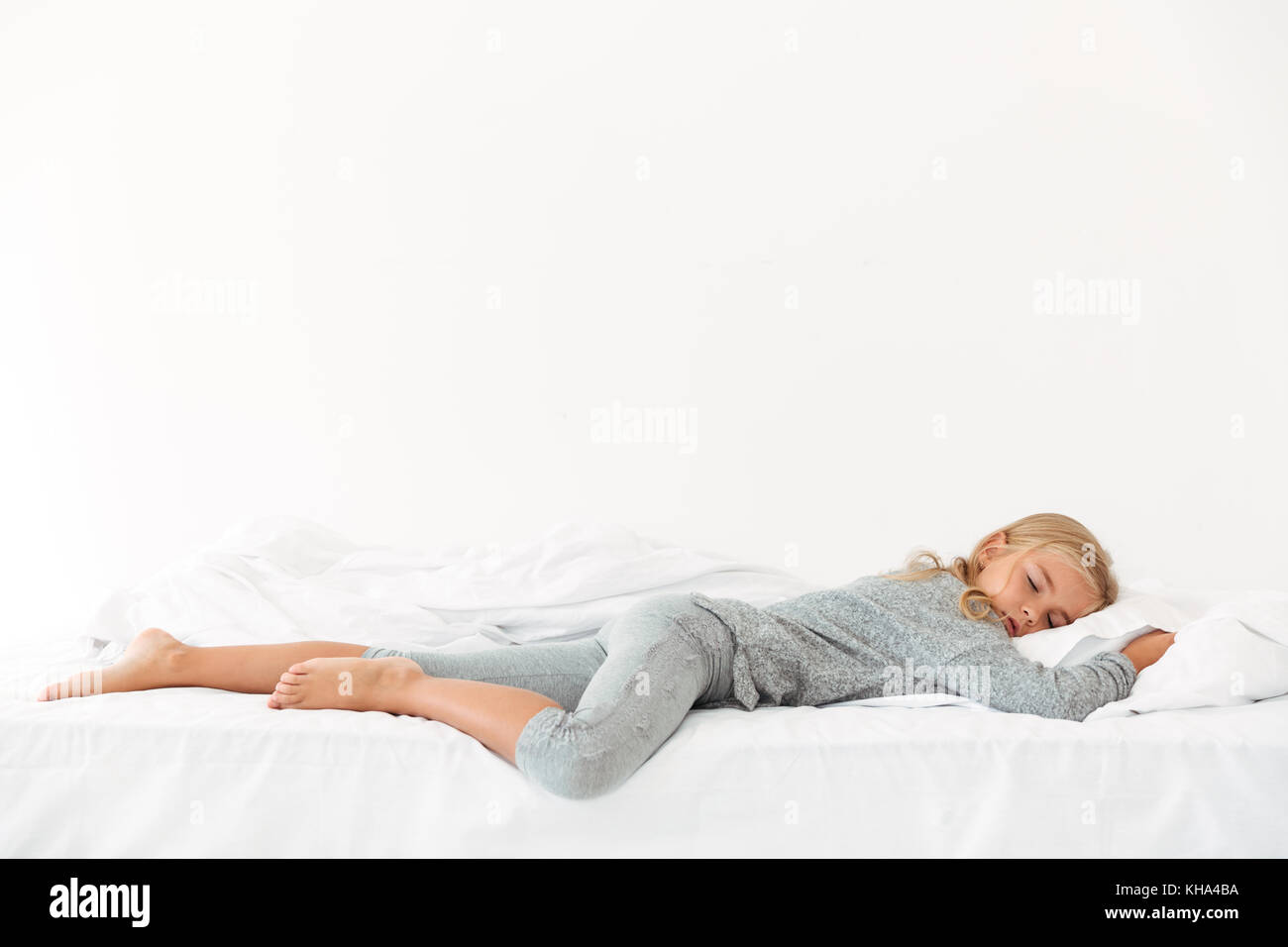 Full length portrait of sleeping peaceful girl in gray pajamas lying in