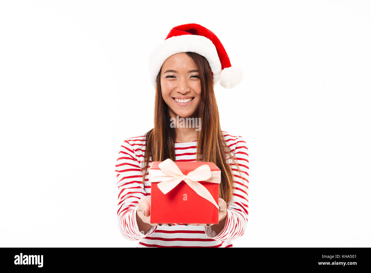 Portrait of a smiling asian girl in christmas hat holding gift box and ...