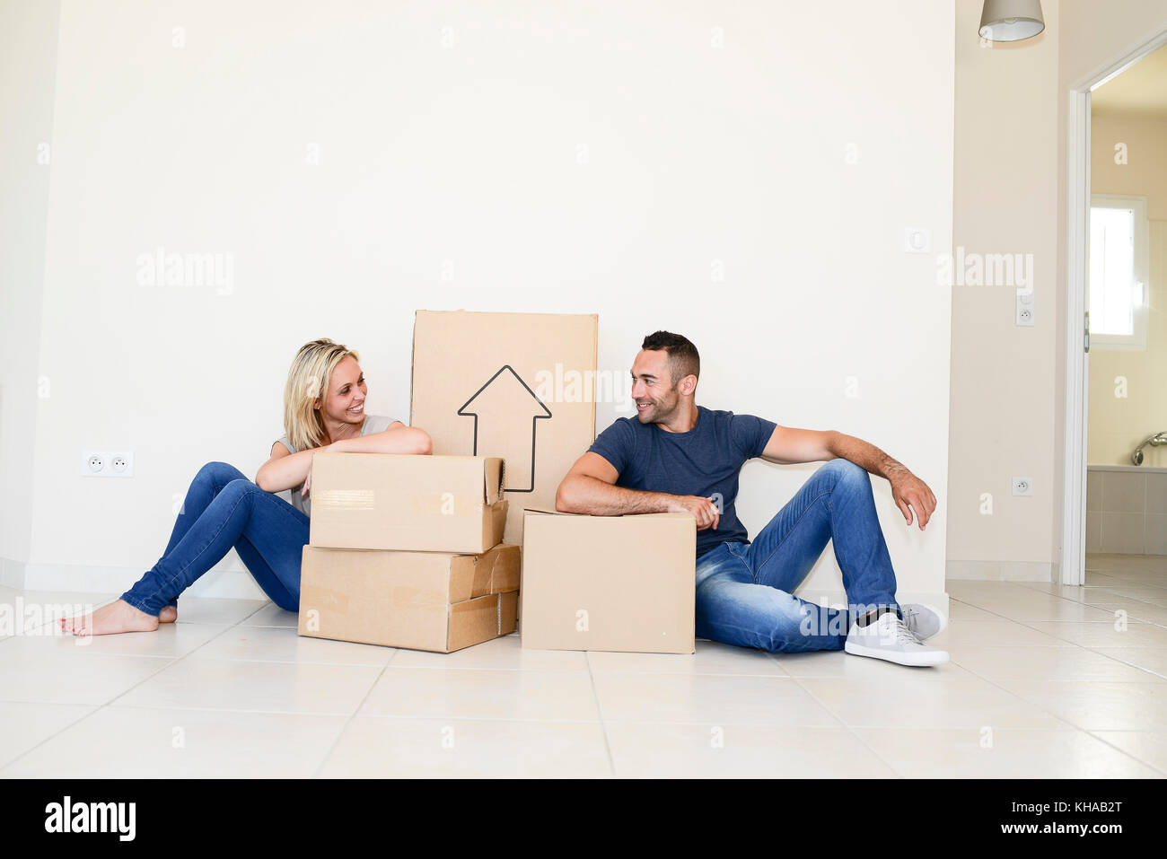 Happy young couple carrying cardboard boxes and moving into their new ...