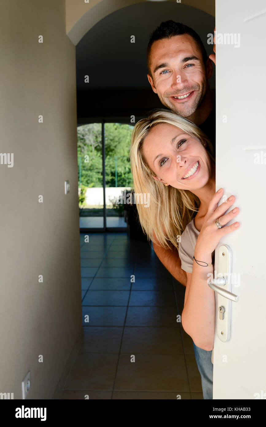 Happy young couple welcoming friends at the front door of new house ...