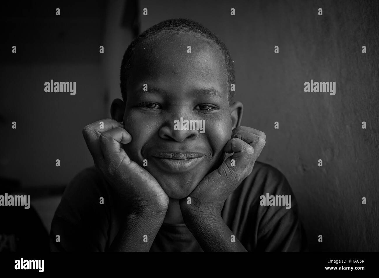 African Boy smiling with his hands under his chin looking towards the camera. Taken in Mali. Stock Photo