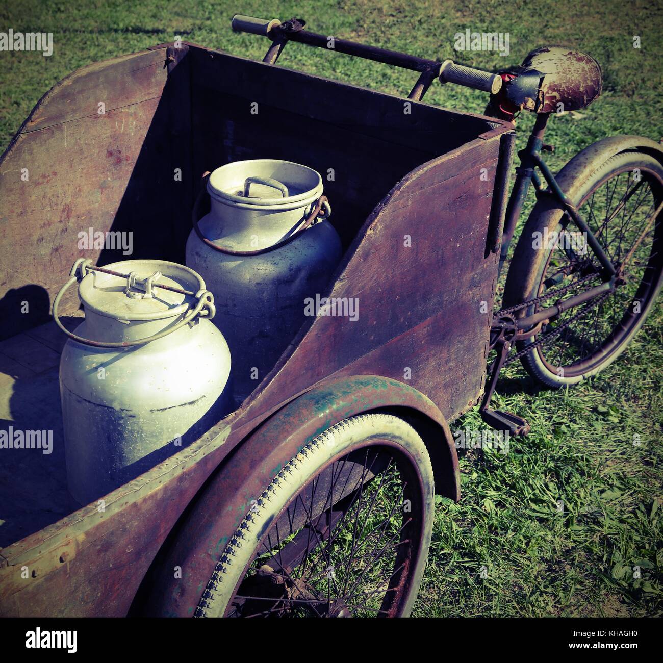 two old milk cans transported by an old wagon with vintage bicycle Stock Photo