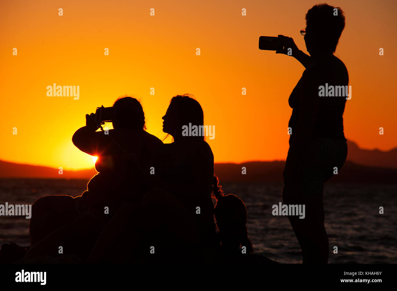 Girls taking selfies during sunset at Lagoon of Maricá, Rio de Janeiro, Brazil Stock Photo