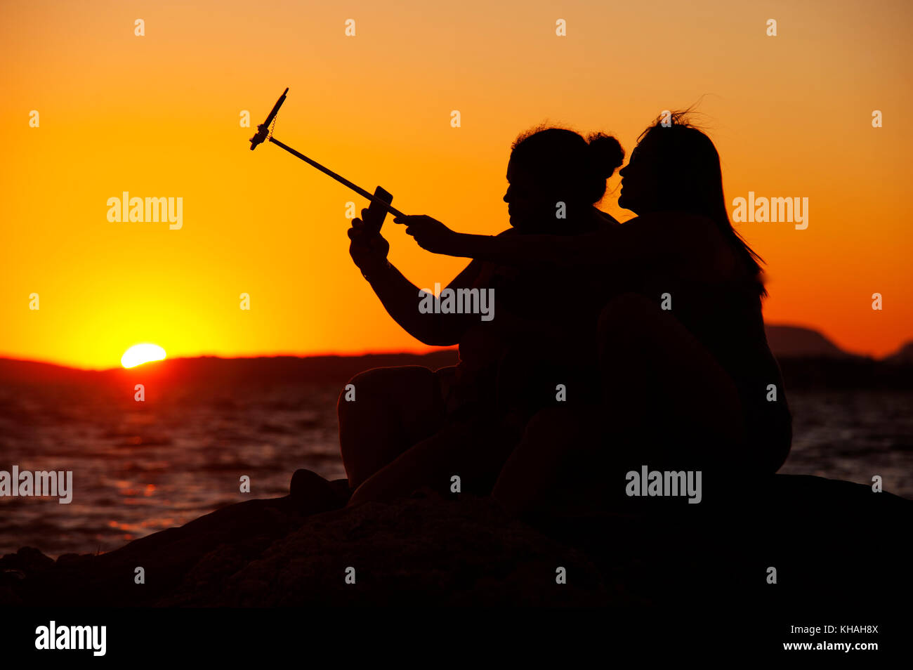 Girls taking selfies during sunset at Lagoon of Maricá, Maricá, Rio de Janeiro, Brazil Stock Photo