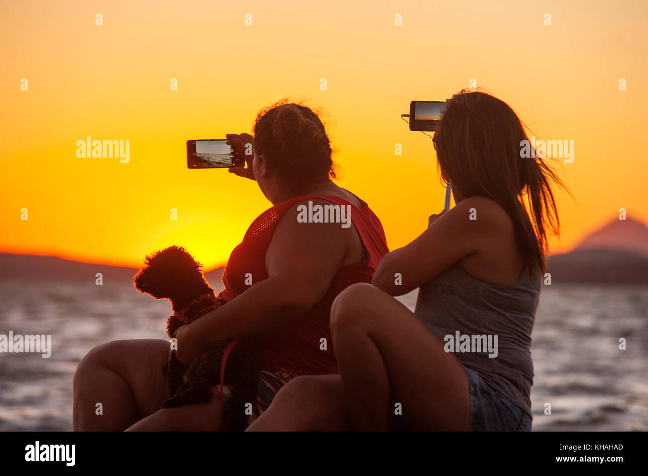 Girls taking selfies during sunset at Lagoon of Maricá, Maricá, Rio de Janeiro, Brazil Stock Photo
