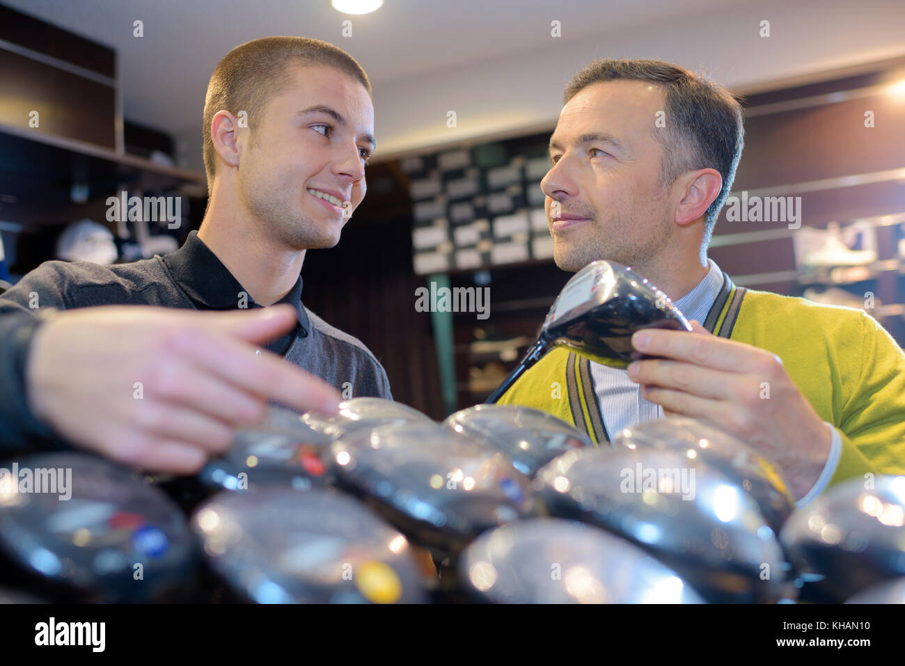 happy seller and customer reviewing clubs in golf store Stock Photo Alamy
