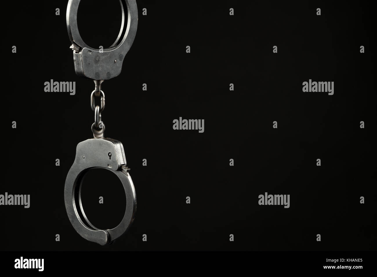 Locked police handcuffs on a black background with text / writing space. Crime / security concept. Stock Photo