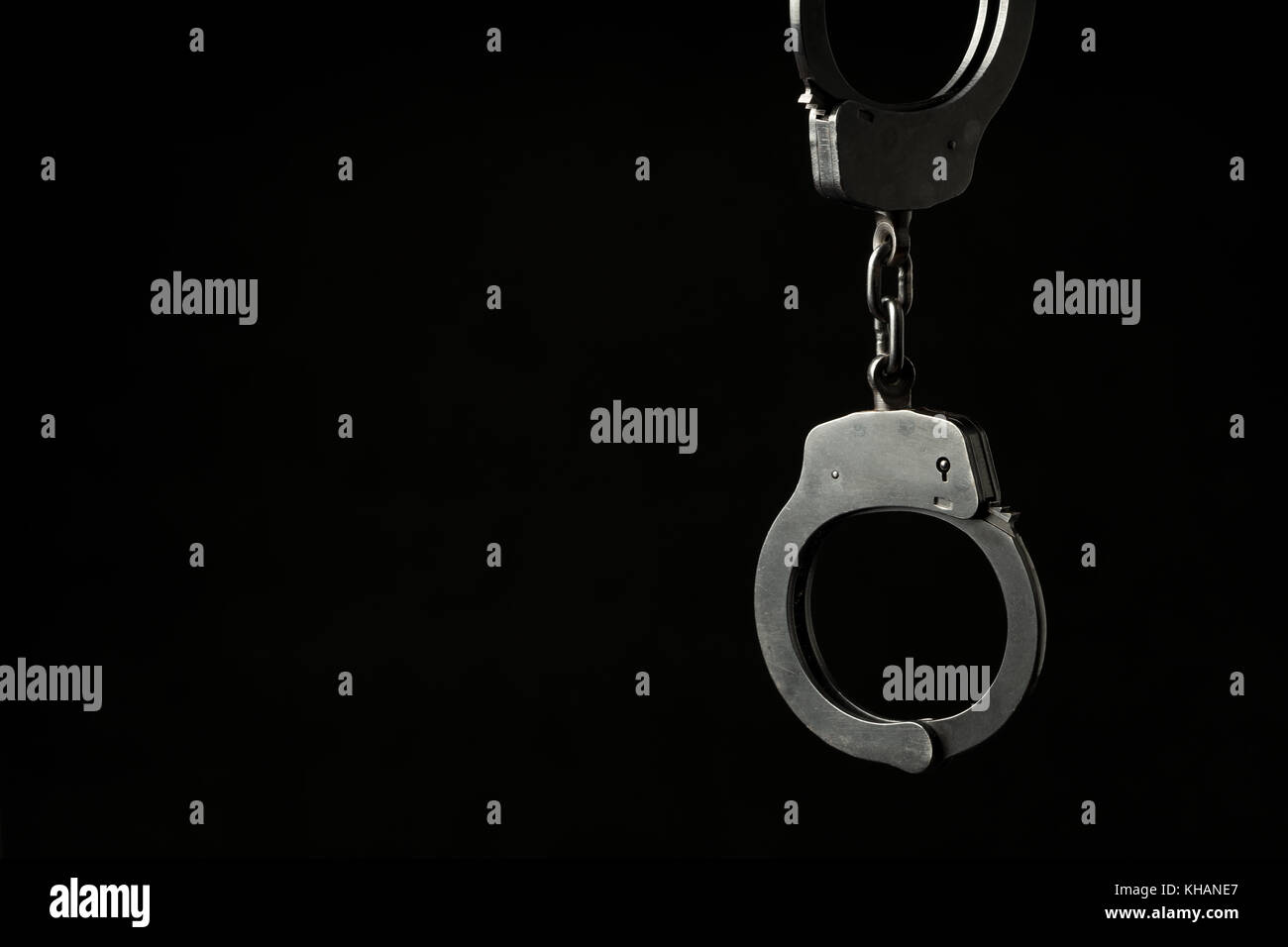 Metal police handcuffs on a black background with text / writing space ...