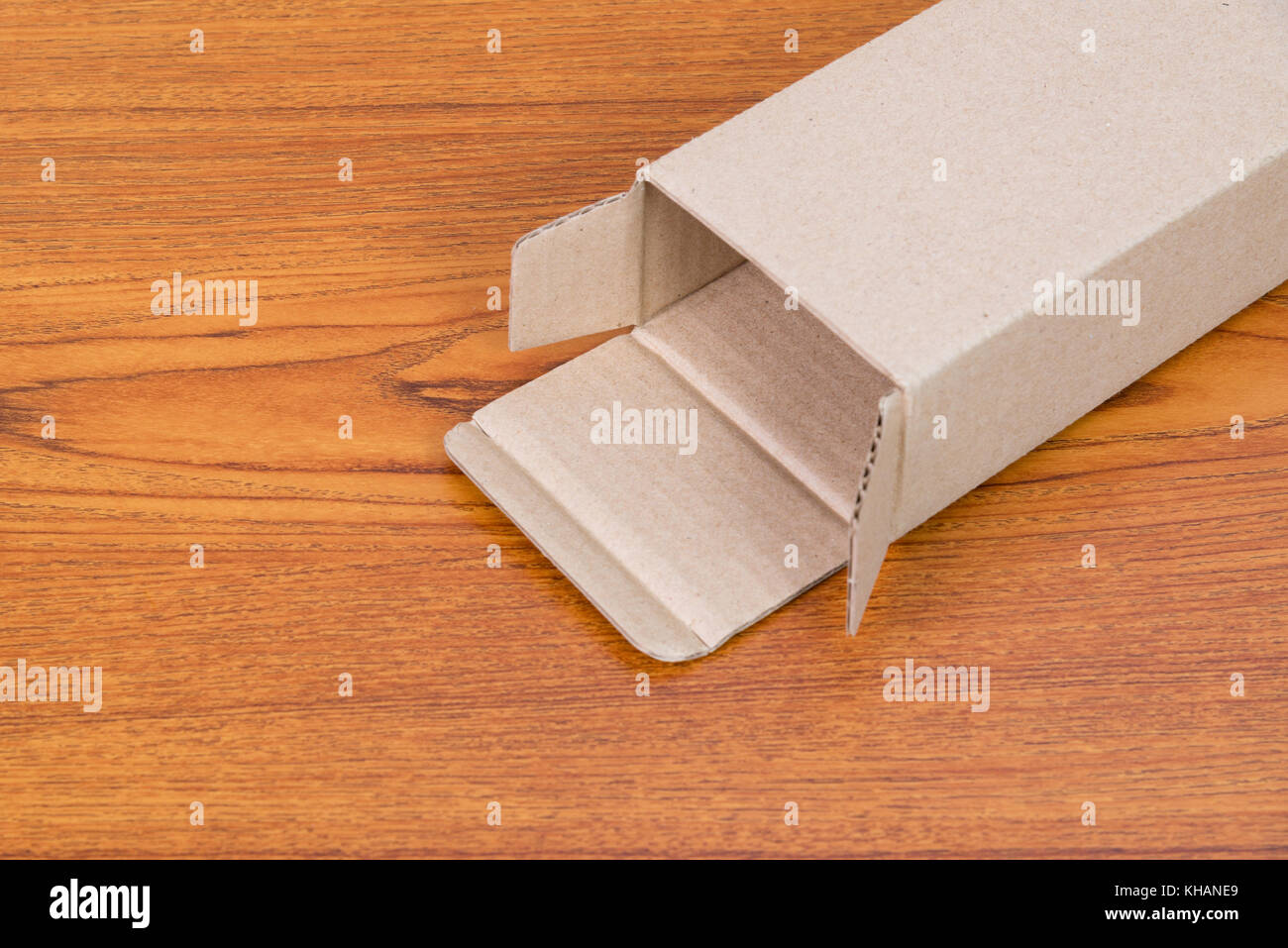 Empty opened brown cardboard box or tray for mock up on bright wooden table with copy space. Stock Photo