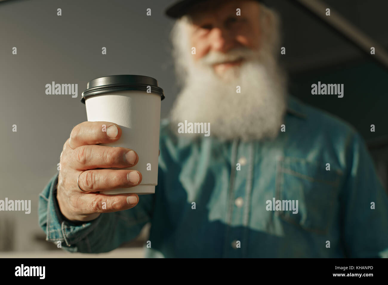 Handsome bearded old man in casual clothes holding a cup of coffee ...