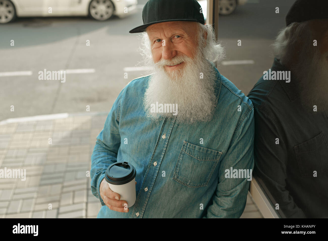 Handsome bearded old man in casual clothes holding a cup of coffee ...