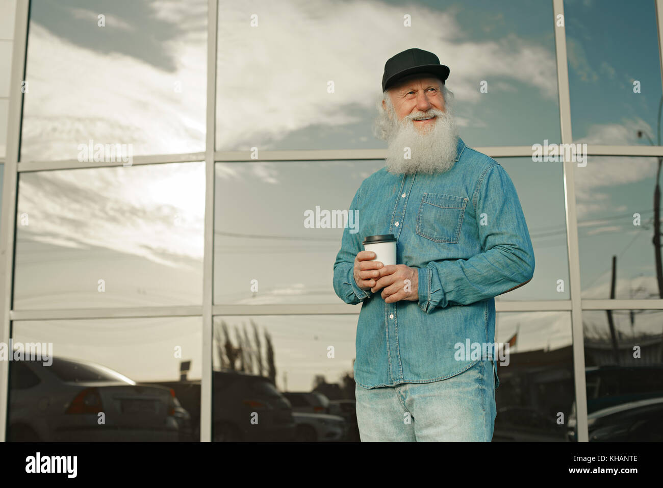Handsome bearded old man in casual clothes holding a cup of coffee ...
