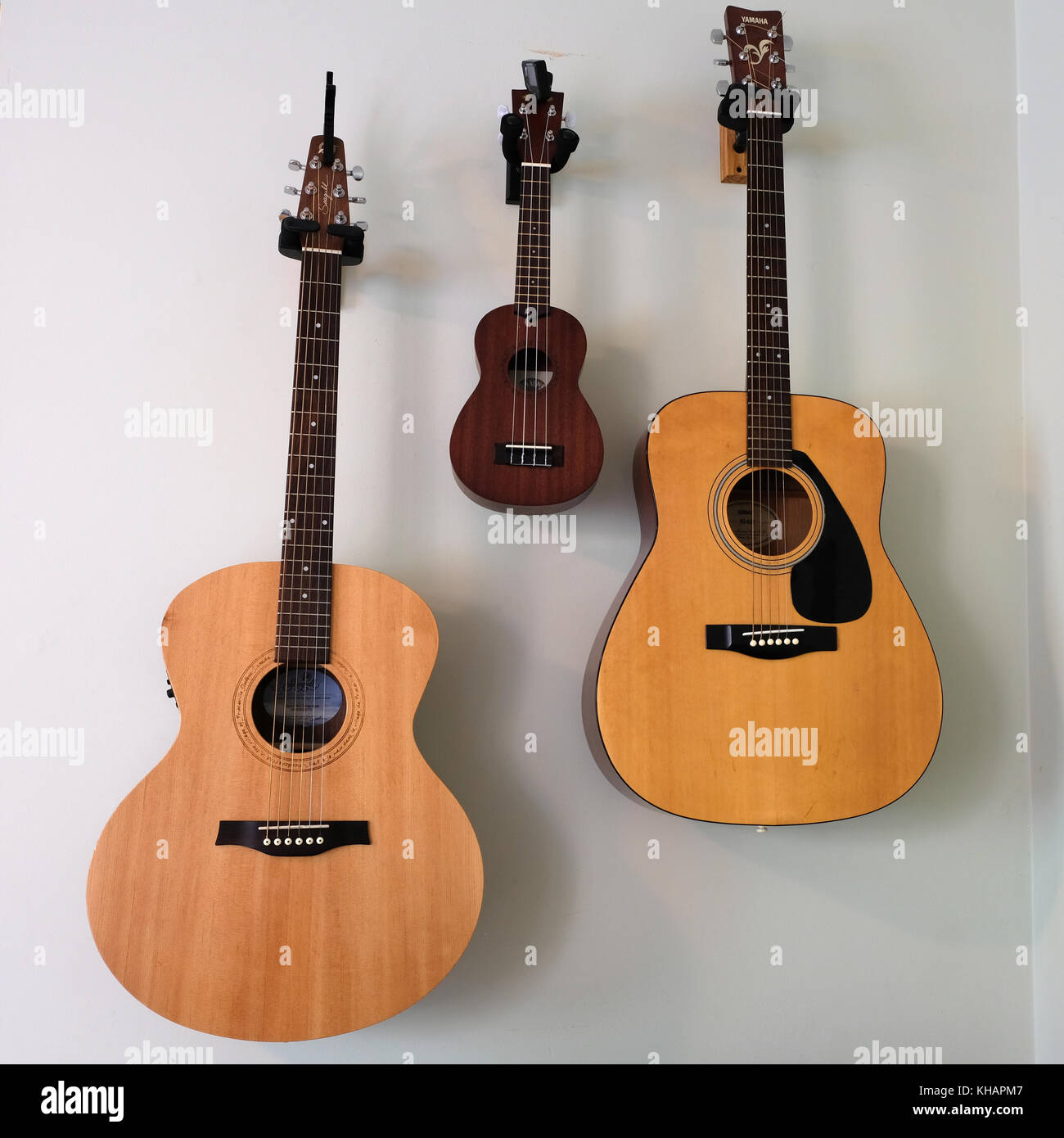 Two guitars and one banjo hanging on wall in symmetrical placement of