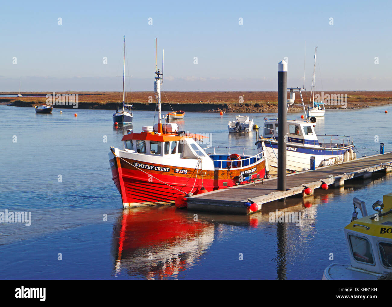 A view of commercial boats tied-up by a pontoon in the North Norfolk harbour of Wells-next-the-Sea, Norfolk, England, United Kingdom. Stock Photo