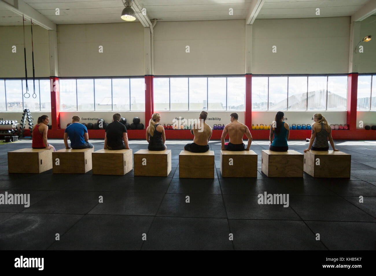 Rear view of men and women sitting on box in fitness club Stock Photo
