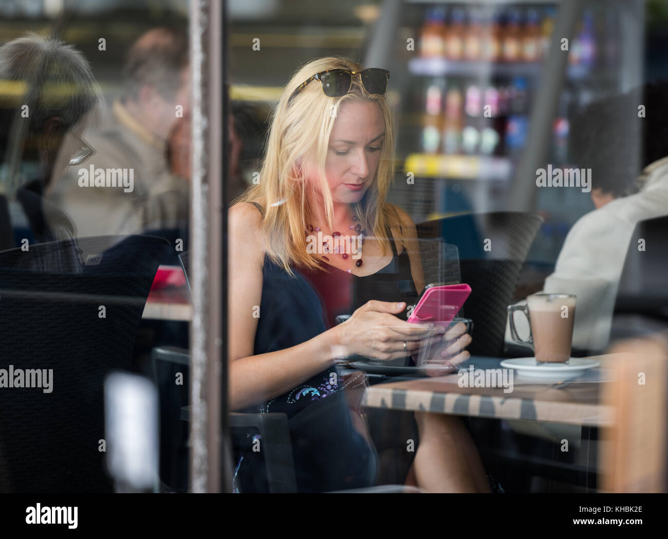 Girl in cafe using smartphone. Stock Photo