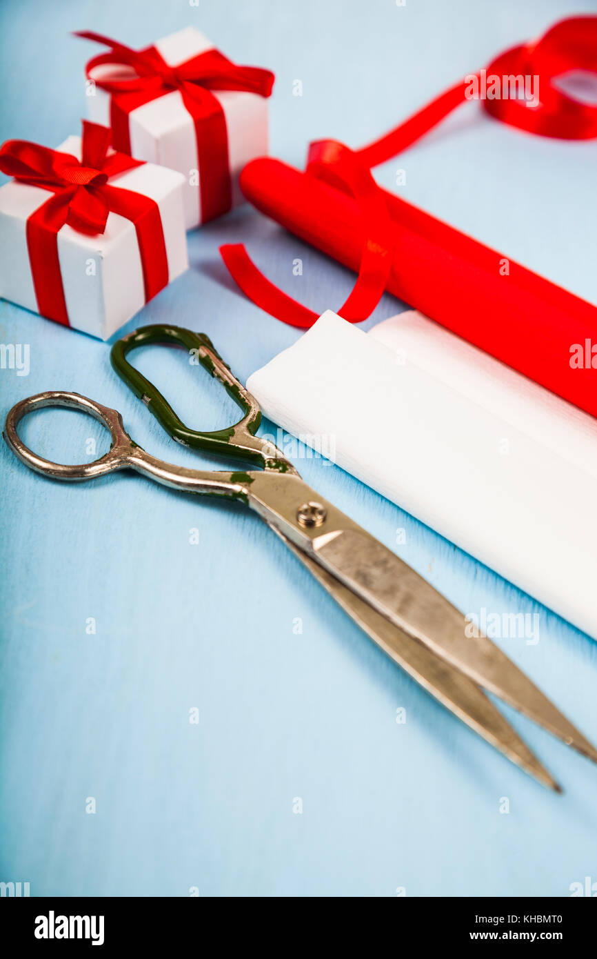 Packing of Christmas gifts. Ribbons, paper, scissors and ornaments on a blue wooden table Stock