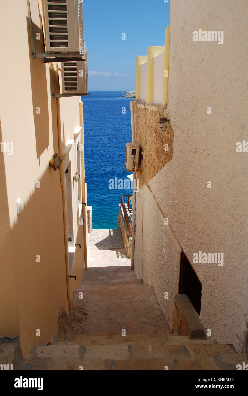 A narrow path leading down between buildings on the harbour front at Emborio on the Greek island of Halki. Stock Photo
