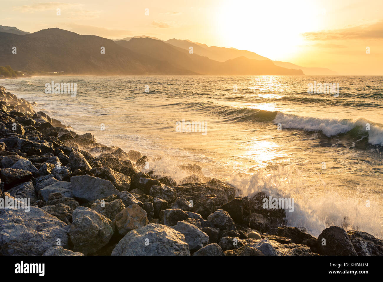 Inspirational beautiful mountains landscape with sea, coast, beach and rocks, high mountains in background at sunrise on Crete Island, Greece. Stock Photo