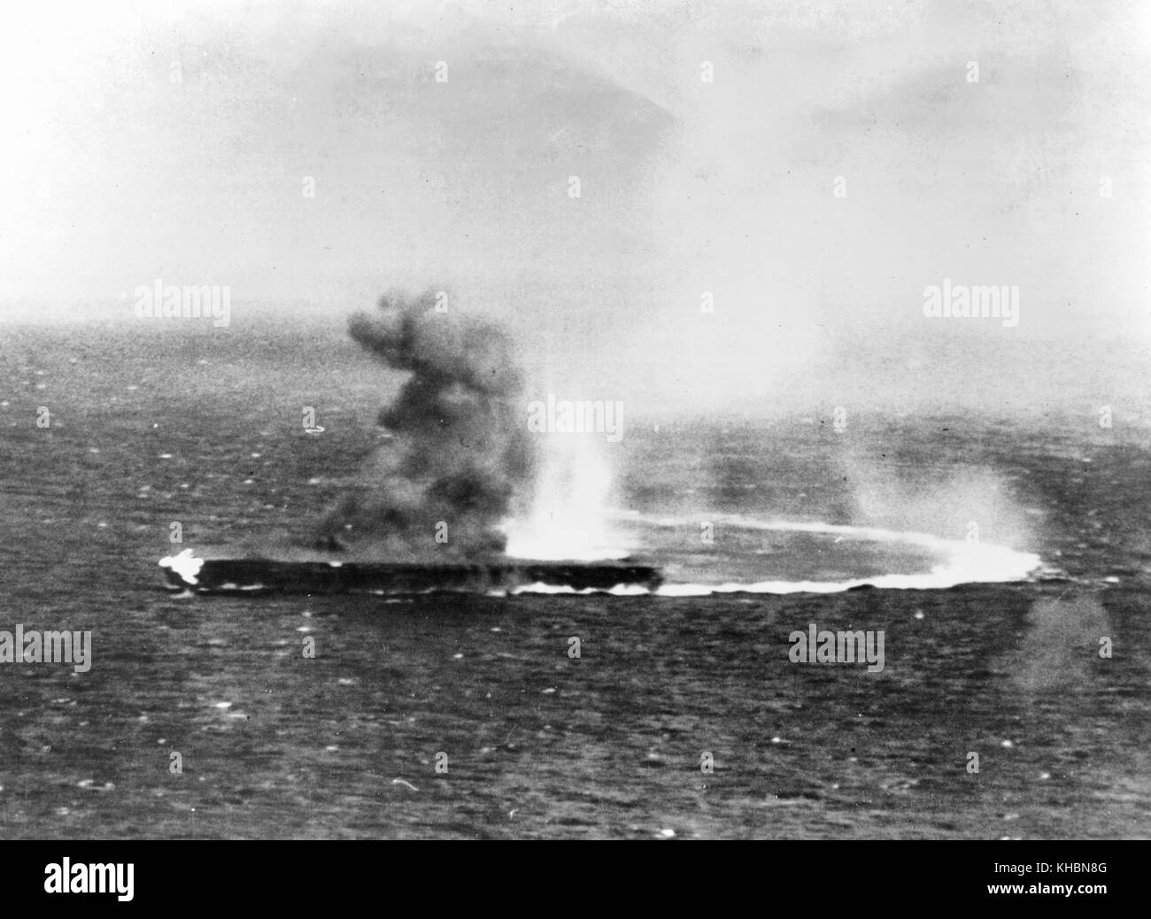 Japanese aircraft carrier Shokaku under dive bombing attacks by USS Yorktown (CV-5) planes, during the morning of 8 May 1942. Flames are visible from a bomb hit on her forecastle. Stock Photo